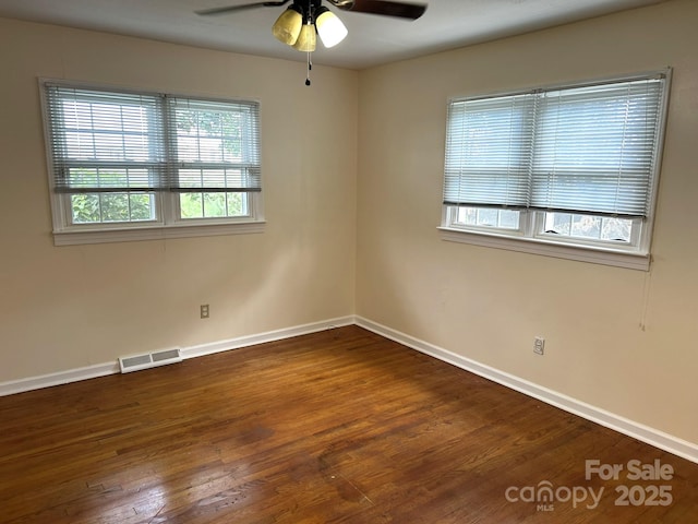 empty room with ceiling fan, dark wood finished floors, and baseboards