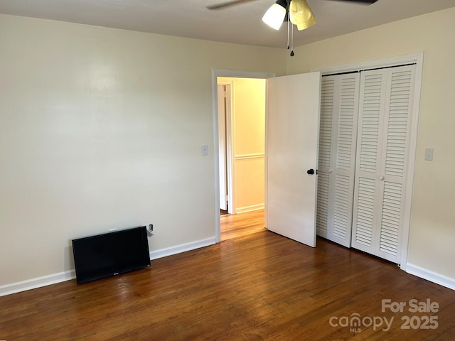 unfurnished bedroom featuring dark wood finished floors, a closet, and baseboards