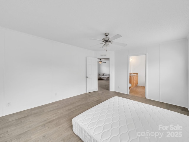 unfurnished bedroom featuring connected bathroom, a ceiling fan, visible vents, and wood finished floors