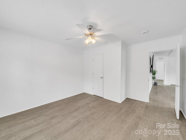 unfurnished room with ornamental molding, light wood-style floors, ceiling fan, and a textured ceiling
