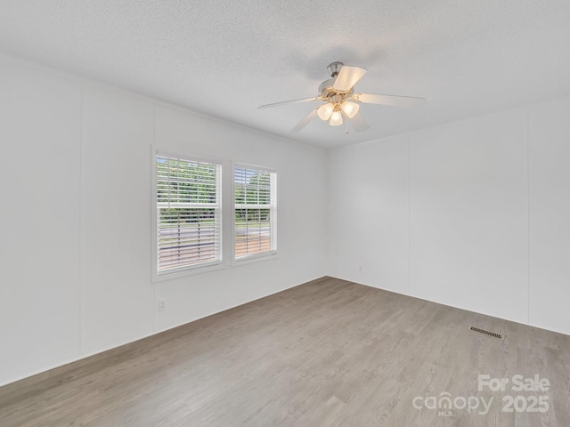 unfurnished room featuring a ceiling fan, visible vents, a textured ceiling, and wood finished floors