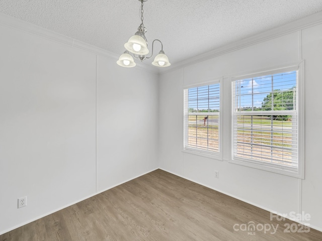 unfurnished room with an inviting chandelier, ornamental molding, a textured ceiling, and wood finished floors