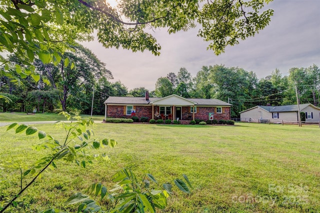 single story home featuring brick siding, a front yard, and a chimney
