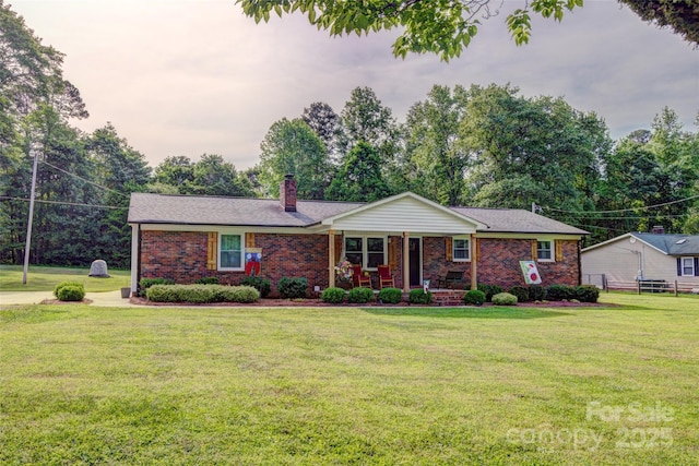 single story home featuring a chimney, a porch, brick siding, and a front yard