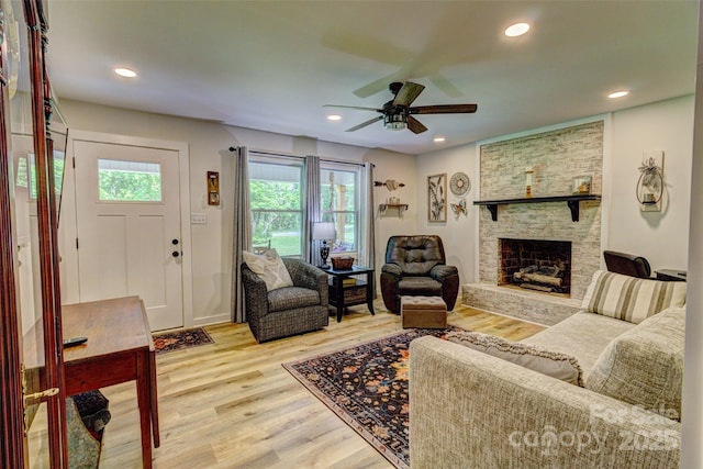 living room featuring light wood-style floors, ceiling fan, a fireplace, and recessed lighting