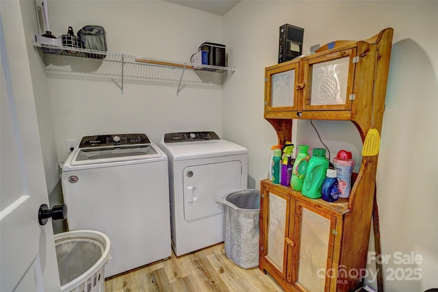 clothes washing area with light wood-style flooring, cabinet space, and washer and dryer