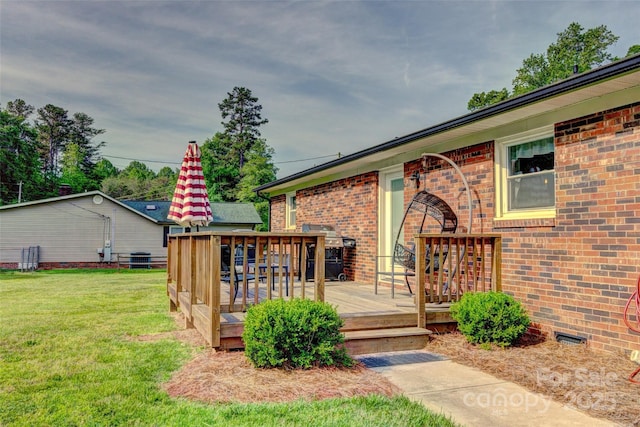 doorway to property with a lawn, a deck, and brick siding