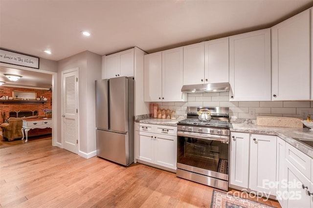 4805 Nesbit Rd, Monroe, NC 28112 - kitchen with light wood-style flooring, under cabinet range hood, white cabinets, and stainless steel appliances