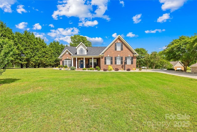 traditional-style house featuring a front yard, brick siding, and covered porch
