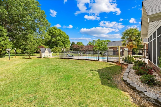 view of yard featuring an outbuilding, a fenced in pool, a storage shed, and fence
