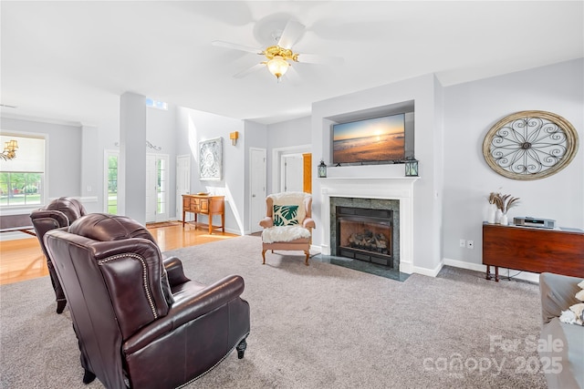 living area with a tiled fireplace, baseboards, and ceiling fan