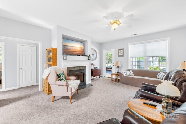 carpeted living room with a fireplace with flush hearth, a ceiling fan, and baseboards