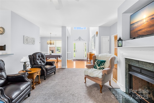 carpeted living room with a fireplace, a chandelier, and a ceiling fan