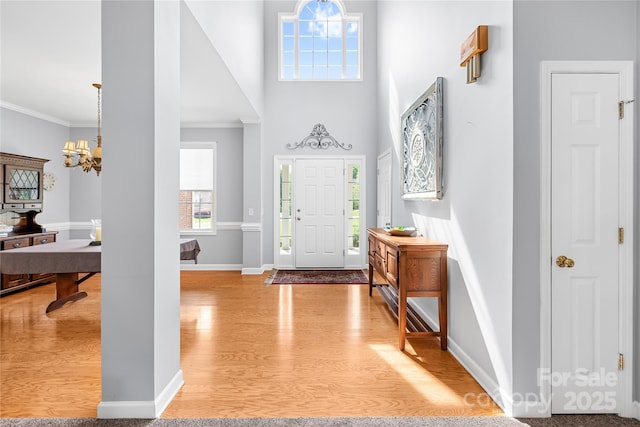 foyer entrance featuring an inviting chandelier, wood finished floors, baseboards, and a healthy amount of sunlight