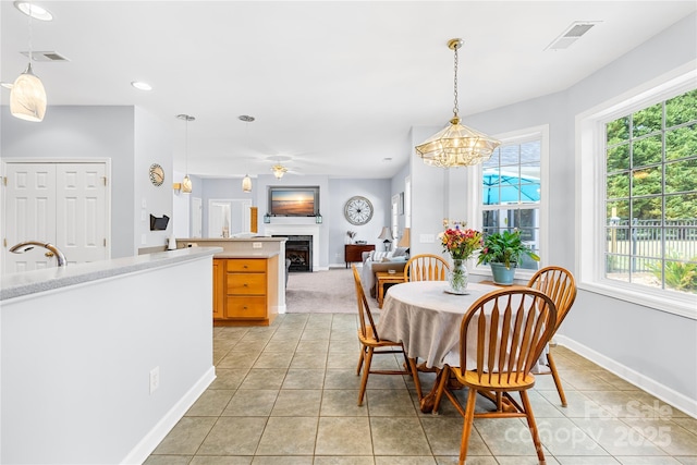 dining space featuring a fireplace, baseboards, light tile patterned floors, a chandelier, and recessed lighting