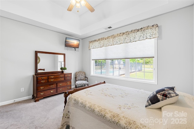bedroom with carpet, a raised ceiling, baseboards, and a ceiling fan