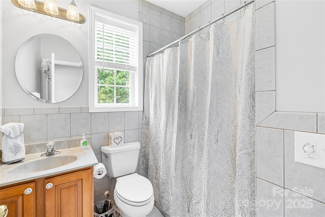 bathroom featuring tile walls, toilet, vanity, and curtained shower