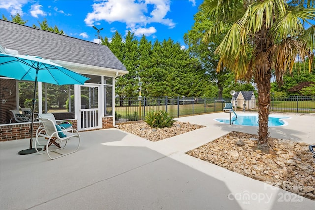 view of patio featuring a sunroom, a fenced backyard, a shed, and an outbuilding