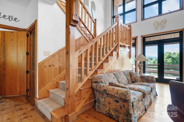 stairway with wood walls, a towering ceiling, a wainscoted wall, and hardwood / wood-style flooring