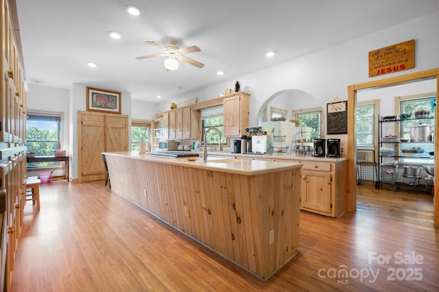 kitchen featuring ceiling fan, a sink, light brown cabinets, light countertops, and light wood-style flooring