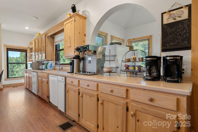 kitchen featuring light brown cabinetry, arched walkways, and a wealth of natural light