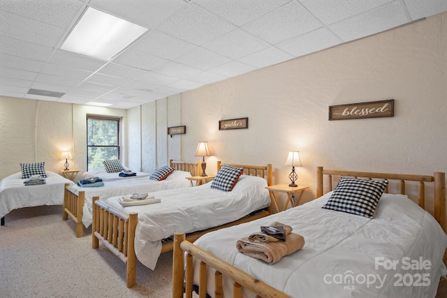 bedroom featuring carpet flooring, a textured wall, and a paneled ceiling