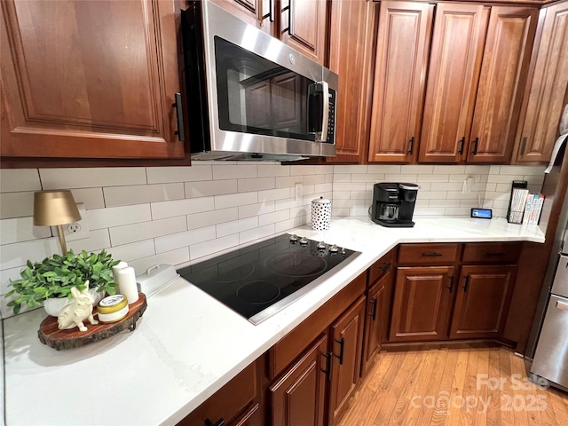 3000 J R Ct, Stanley, NC 28164 - kitchen featuring black electric stovetop, light countertops, light wood-style flooring, stainless steel microwave, and tasteful backsplash