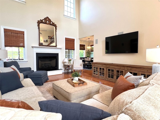 3000 J R Ct, Stanley, NC 28164 - living room with a notable chandelier, a high ceiling, a glass covered fireplace, and wood finished floors