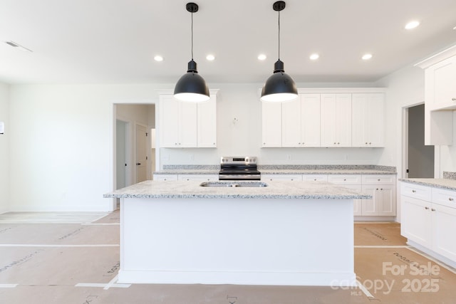 kitchen featuring white cabinets, recessed lighting, and an island with sink