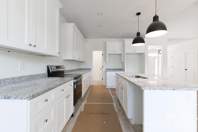 kitchen with hanging light fixtures, light stone countertops, a center island with sink, white cabinets, and electric stove