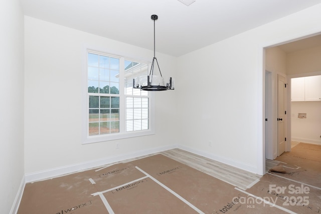 unfurnished dining area featuring baseboards, wood finished floors, and a chandelier
