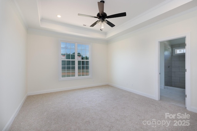 carpeted spare room featuring ceiling fan, visible vents, ornamental molding, and a raised ceiling