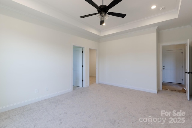 unfurnished bedroom with baseboards, a tray ceiling, and light colored carpet