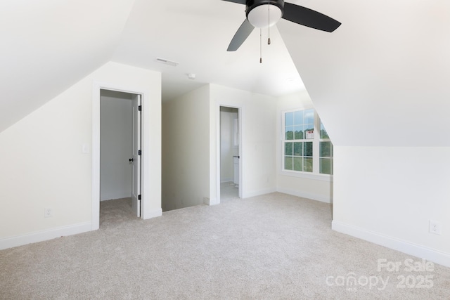 additional living space with carpet flooring, visible vents, a ceiling fan, baseboards, and vaulted ceiling