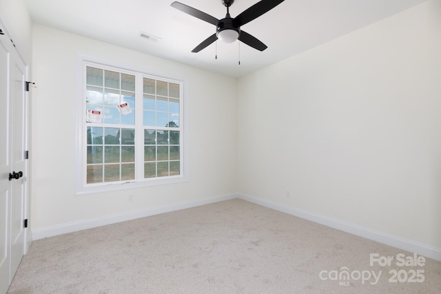 carpeted spare room with baseboards, a ceiling fan, and visible vents
