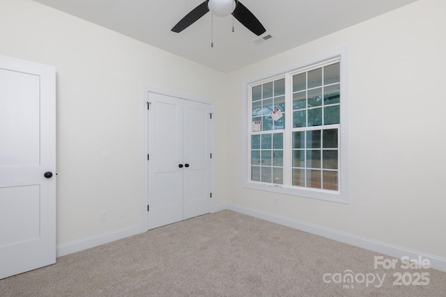 unfurnished bedroom with carpet flooring, ceiling fan, baseboards, visible vents, and a closet
