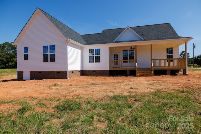 back of property with a shingled roof and crawl space