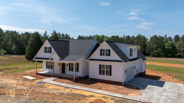 modern inspired farmhouse with covered porch, an attached garage, and driveway