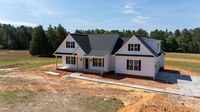 view of front of property with a garage, a view of trees, concrete driveway, and a porch
