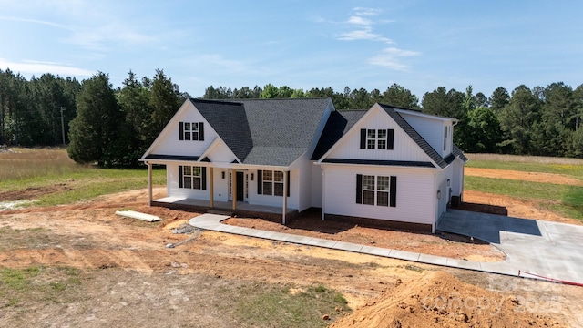 view of front facade featuring a porch, a view of trees, and driveway