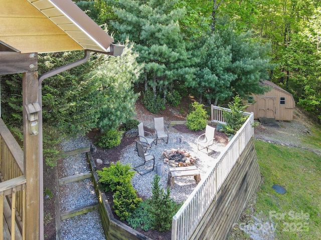 view of yard featuring a storage unit, an outdoor structure, and an outdoor fire pit