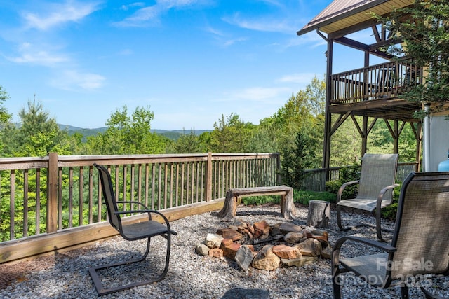 view of patio with a deck with mountain view and an outdoor fire pit
