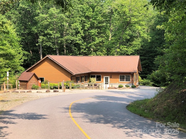 view of front of home with curved driveway and a forest view