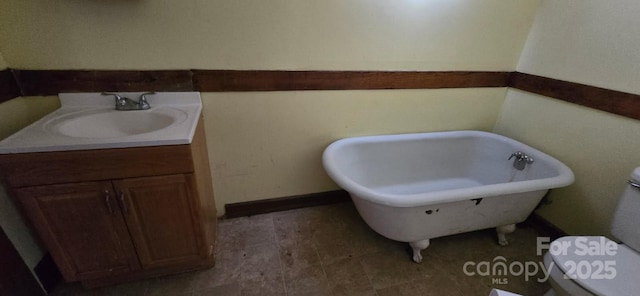 bathroom featuring toilet, a freestanding bath, and vanity