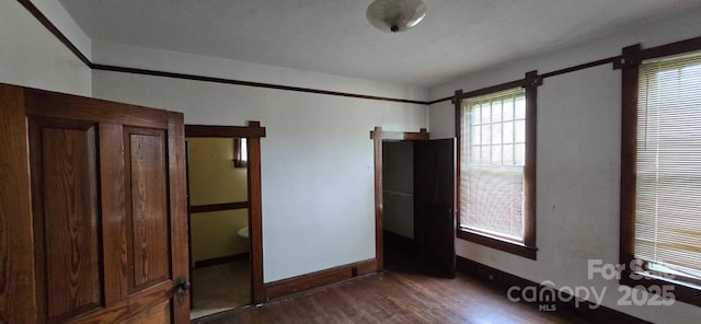 unfurnished bedroom with baseboards and dark wood-style floors