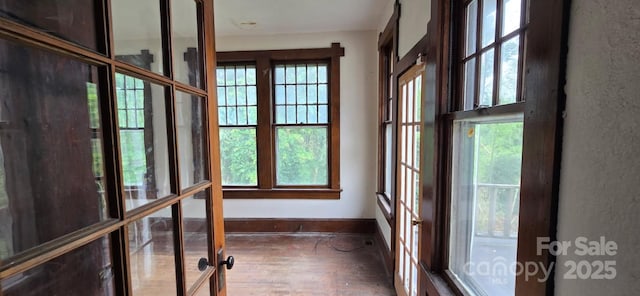 empty room with baseboards, a healthy amount of sunlight, and wood finished floors