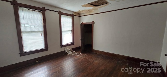 spare room featuring baseboards and dark wood finished floors