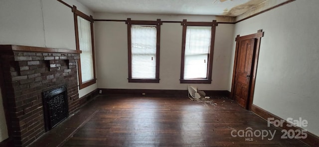 unfurnished living room featuring baseboards, dark wood-style floors, and a fireplace