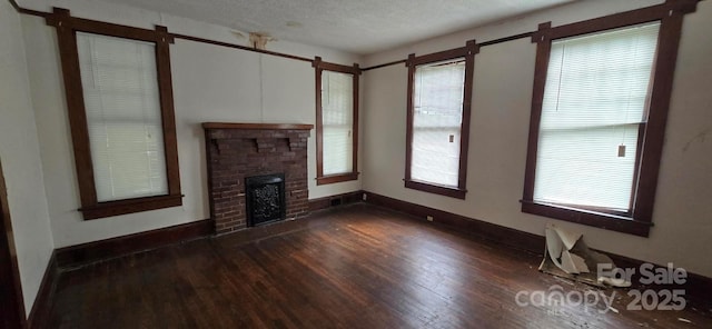 unfurnished living room with baseboards, a textured ceiling, dark wood-style floors, and a fireplace