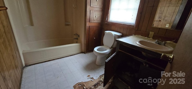 bathroom with vanity, tile patterned floors, toilet,  shower combination, and wooden walls